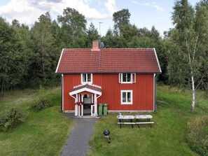 A red house with a porch, a satellite dish, and picnic tables. - 7 Person Holiday Home in Lekeryd (Lekeryd)