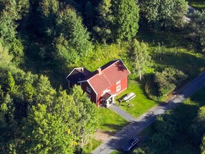 A red house with a sloped roof surrounded by dense green trees. - 7 Person Holiday Home in Lekeryd (Lekeryd)