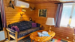 L’intérieur d’un chalet accueillant, avec un canapé en bois, une petite table ronde et un tapis coloré.