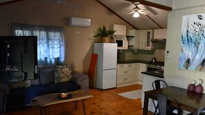 Un espacio habitable compacto con kitchenette, comedor y zona de estar.