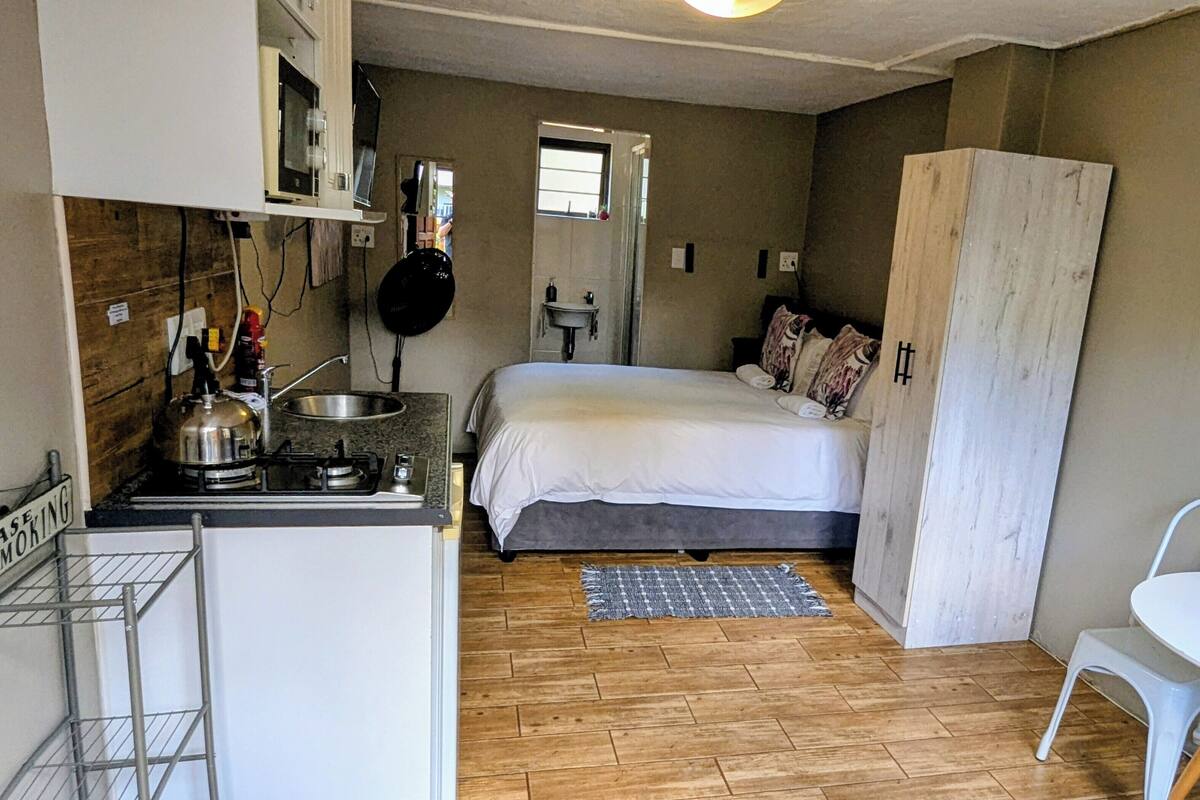 Une pièce de taille modeste comprenant un lit, une petite kitchenette, un coin repas et une fenêtre.