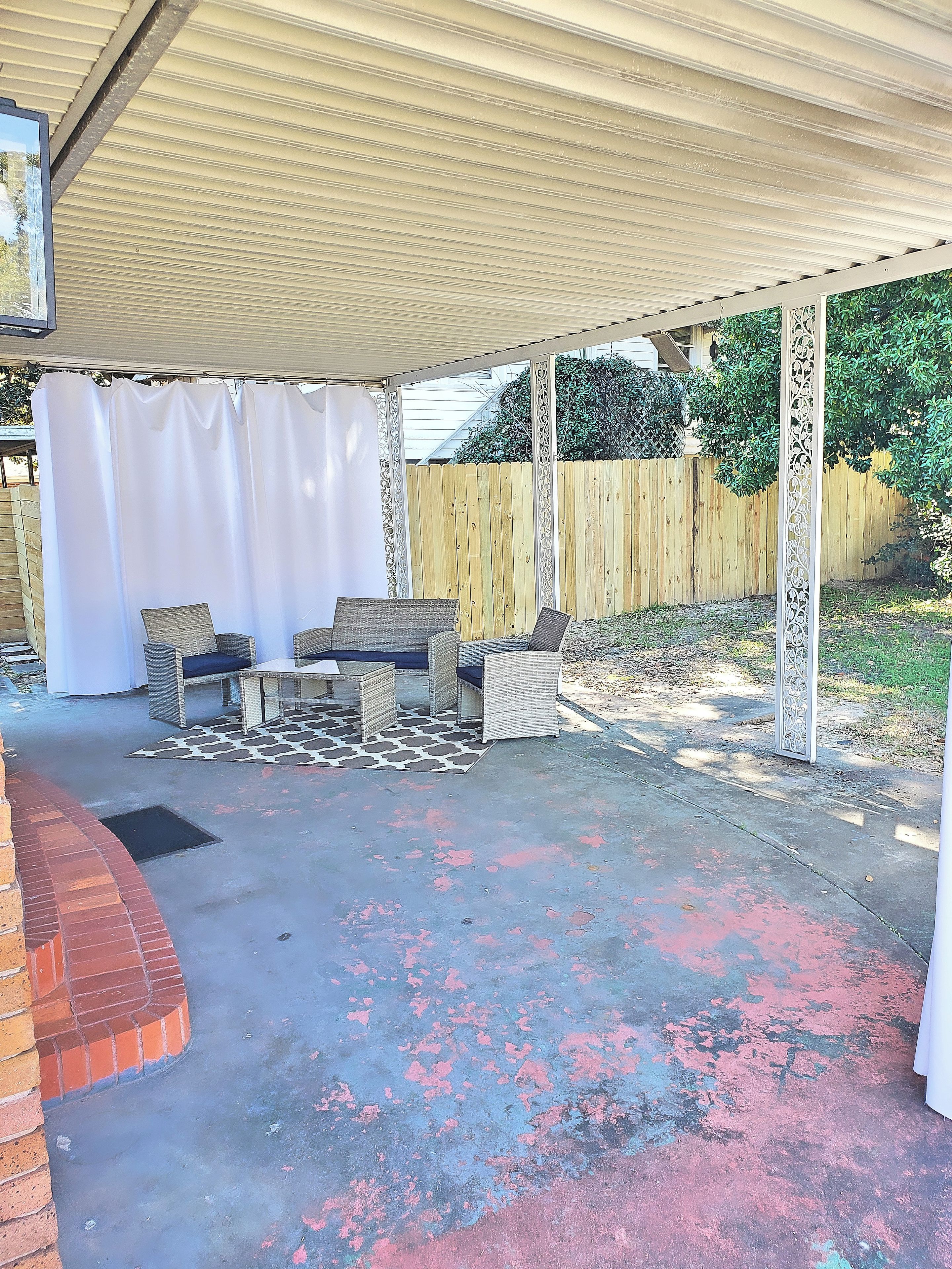 An outdoor patio with wicker furniture and a covered area.
