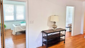 A room with a bed, a table with a lamp, and a wardrobe. - Charming Home on Porter Avenue! (Biloxi)