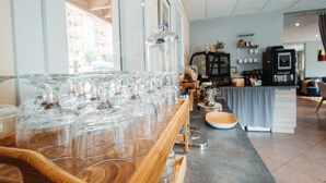 Zona de bar con una barra larga, cristalería y una máquina de café.