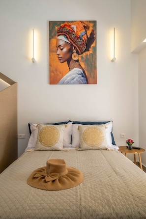 Ein Schlafzimmer mit einem Bett, zwei Wandlampen, einem Gemälde und einem kleinen Tisch mit einer Vase.