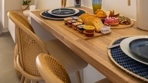 En matplats med ett träbord dukat för två personer, en tv som är monterad på väggen och en dekorativ träskulptur.