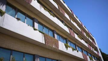 Un edificio de varios pisos con balcones, ventanas amplias y cielo despejado.