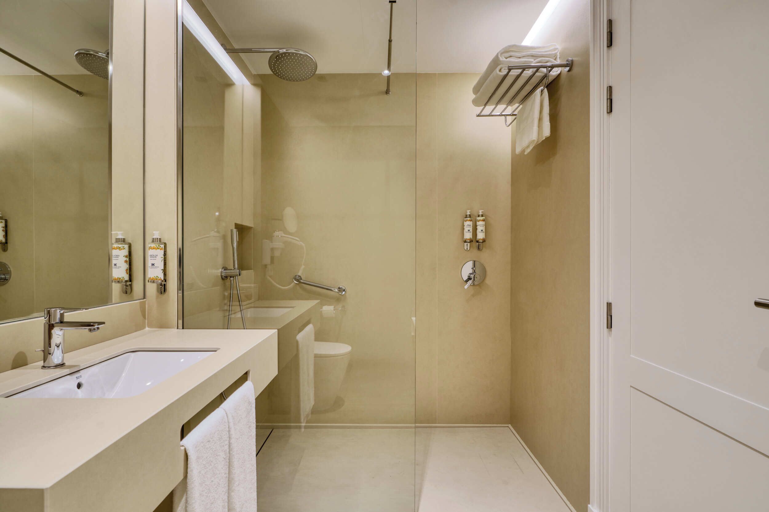 Un baño moderno con un espejo grande, dos lavamanos, una ducha y un inodoro.