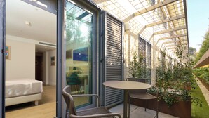 A modern room with a bed, a glass door leading outside, and a small table with chairs. - Hotel Ybarra Sevilla (Seville)