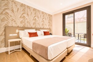 Cama doble con cabecera, mesitas de noche y vistas al exterior por un ventanal corredero.