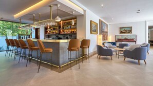 A modern bar area with bar stools, a counter, and a variety of bottles. - Hotel Ybarra Sevilla (Seville)