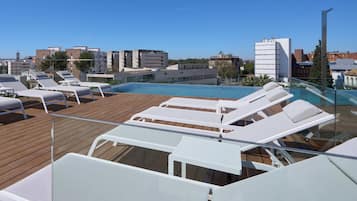 A rooftop pool area with lounge chairs and a clear view of the cityscape.