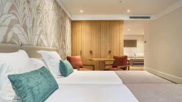 A hotel room with a large bed, a small round table, two chairs, and a wooden wardrobe.