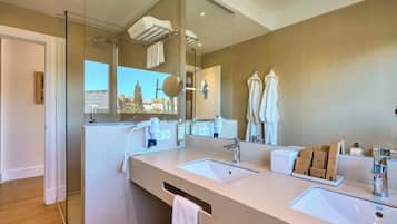 A modern bathroom with two sinks, a large mirror, and a view of a building outside.