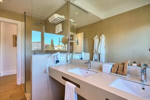 A modern bathroom with two sinks, a large mirror, and a view of a building outside.