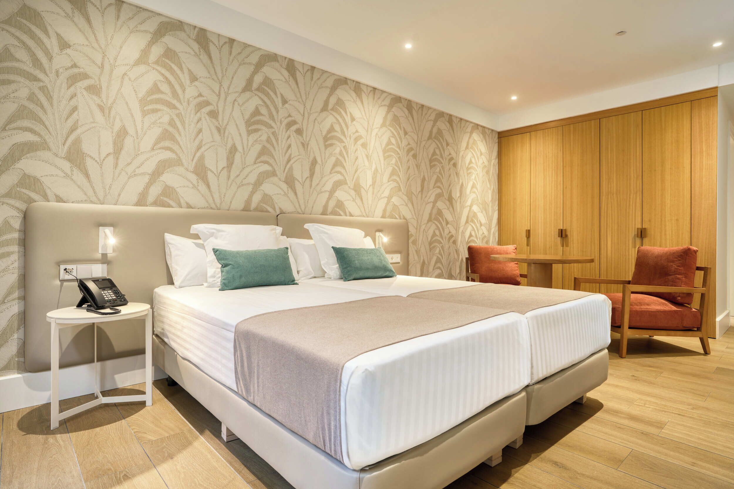 A double bed with a headboard, bedside tables, a telephone, and a chair.
