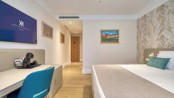 Habitación de hotel con cama, escritorio, silla y un cuadro en la pared.