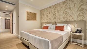 A double bed with a headboard, a bedside table with a phone, and a wall with a patterned wallpaper.