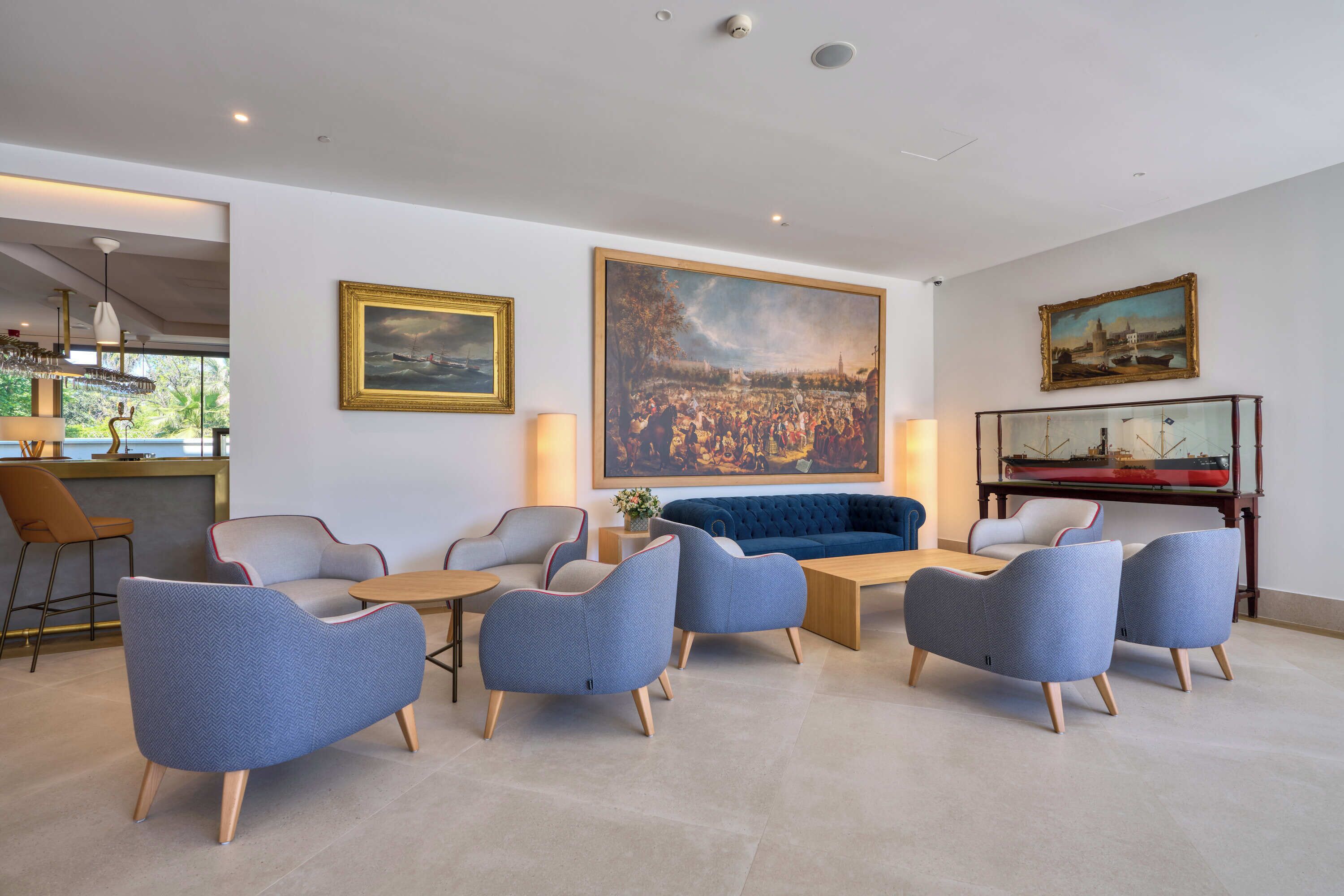 A modern living room with a sofa, armchairs, a coffee table, and a painting of a landscape.