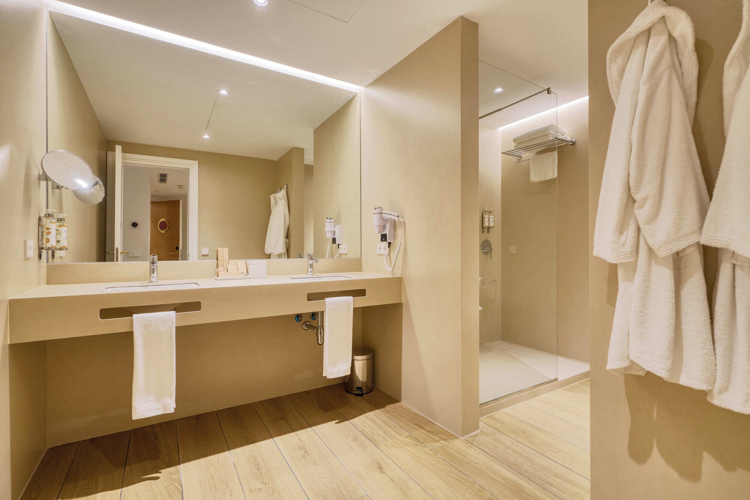 Un baño moderno con lavamanos doble, un espejo grande, toallero y zona de ducha.