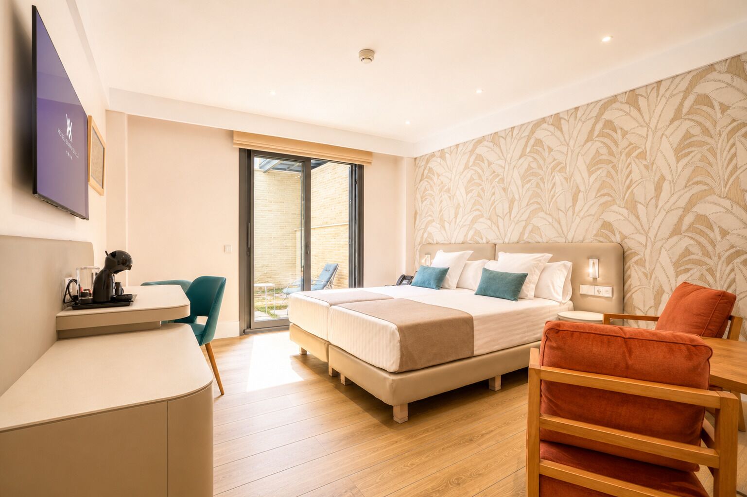 A modern hotel room with a bed, a desk, a chair, and a balcony with a view.