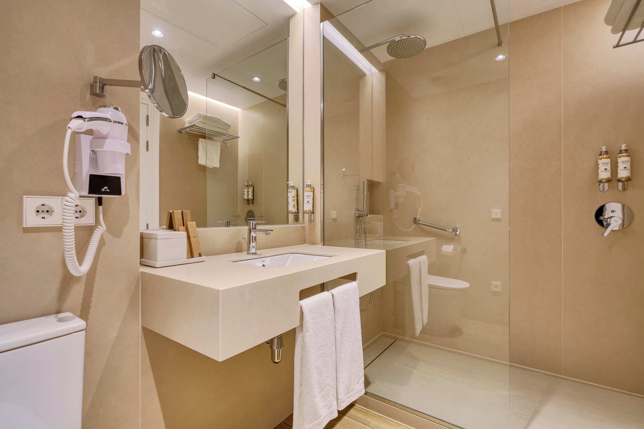 Un baño moderno con lavamanos, espejo y ducha.