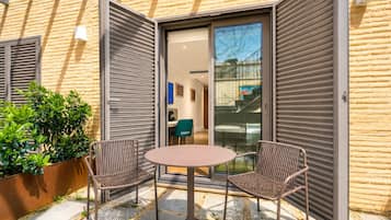 An open sliding door leading to a room with a desk, chair, and a view of the street.