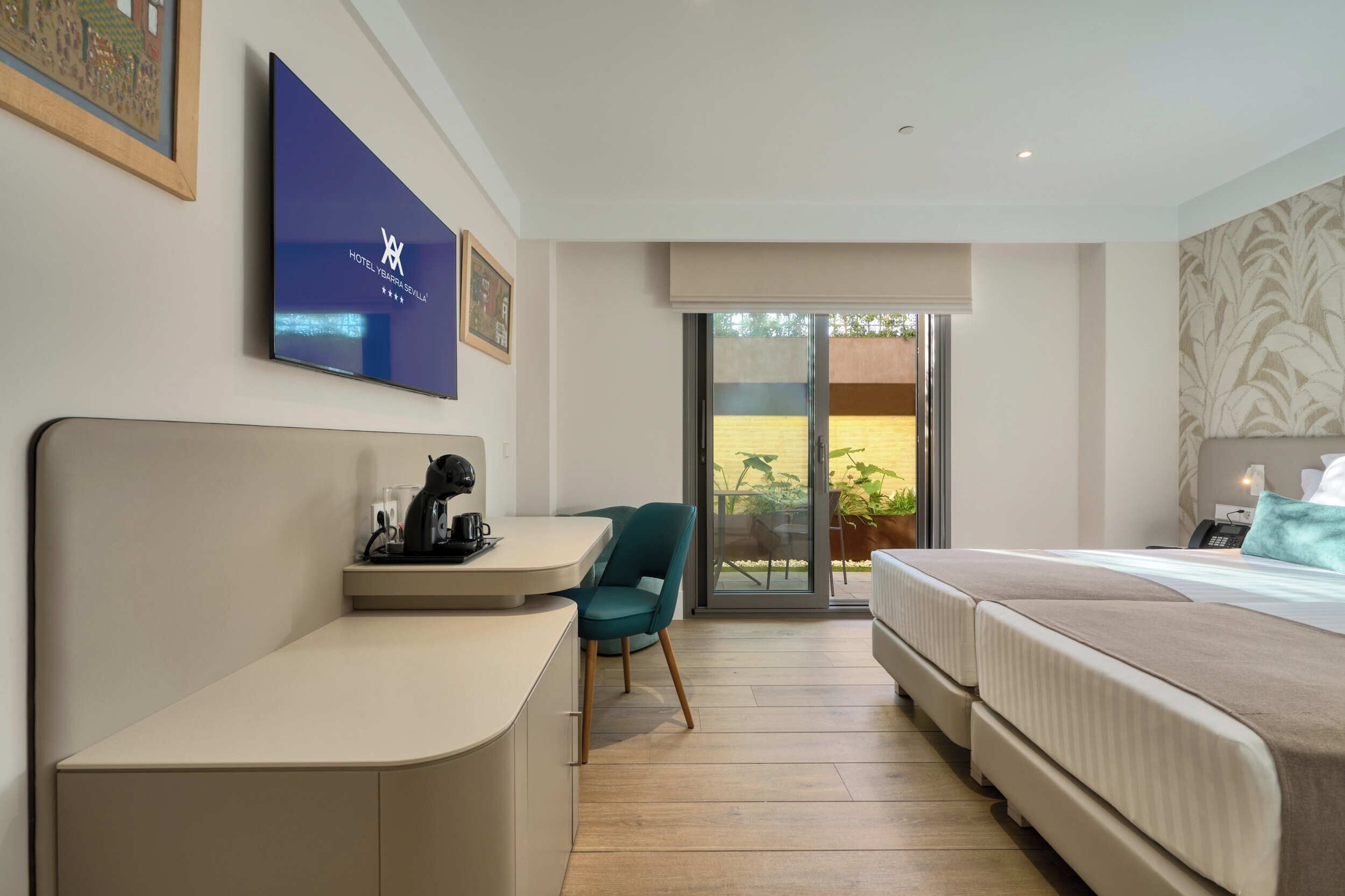 A hotel room with a bed, a desk, a chair, a television, and a sliding glass door to the outside.