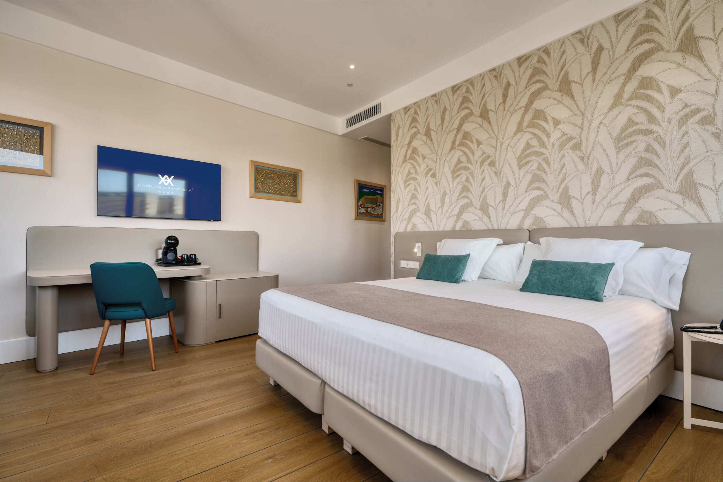 A hotel room with a bed, a desk, a chair, and a television.
