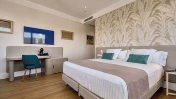A hotel room with a bed, a desk, a chair, and a television.