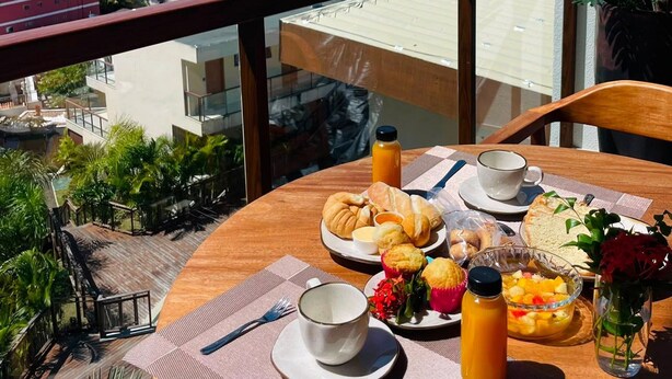 A balcony with a table set for breakfast overlooking a coastal view. - Mar Dá Liberdade com Amerigo Vespucci (Cairu)