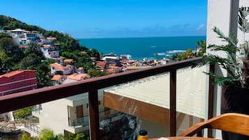 A balcony with a table set for breakfast overlooking a coastal view.