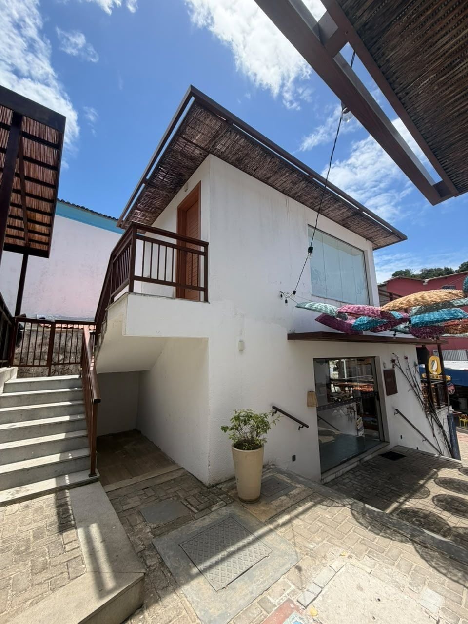 A two-story building with a staircase leading to the upper floor, a potted plant, and a covered entrance area.