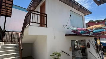 A two-story building with a staircase leading to the upper floor, a potted plant, and a covered entrance area.