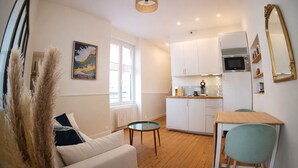 Ett kompakt bostadsutrymme med en soffa, ett matbord och ett litet kök.
