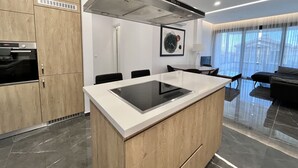 Eine moderne Küche mit Kochinsel, Backofen und Dunstabzugshaube aus Edelstahl.