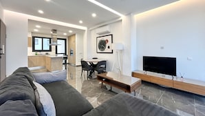 Ein modernes Wohnzimmer mit einer Couch, einem Fernseher und einem Essbereich mit Stühlen und einem Tisch.