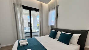 Ein modernes Hotelzimmer mit einem großen Bett, einem Balkon und Blick auf die Stadt.