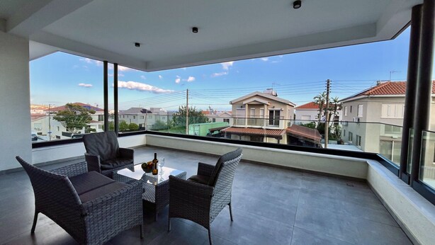 Ein Balkon mit Korbmöbeln, einem Tisch und freiem Blick auf die Umgebung.