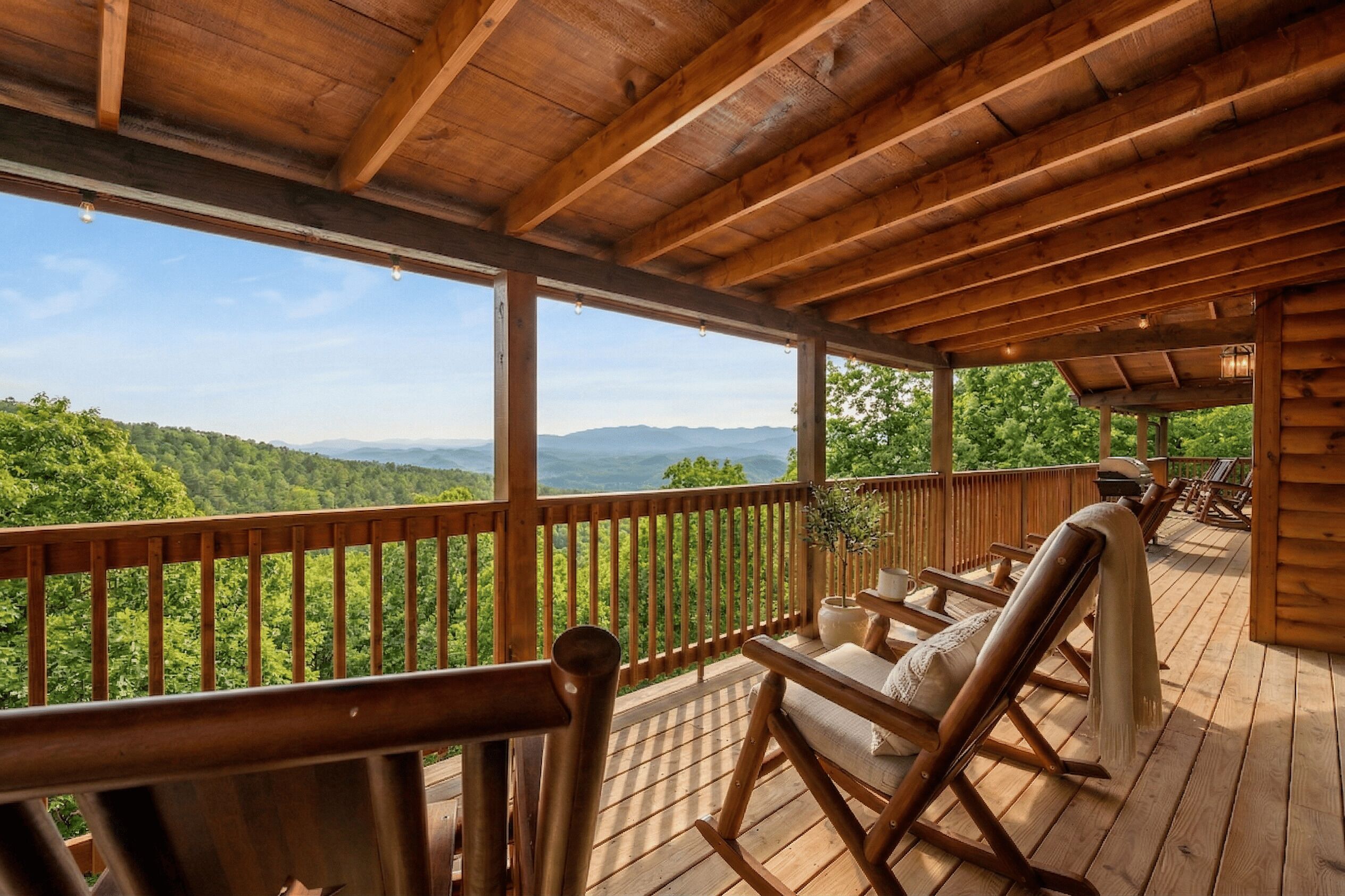 A wooden deck with rocking chairs and a view of a forested mountain range.