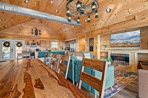 Interior espacioso de una cabaña de madera con comedor, cocina y sala de estar.