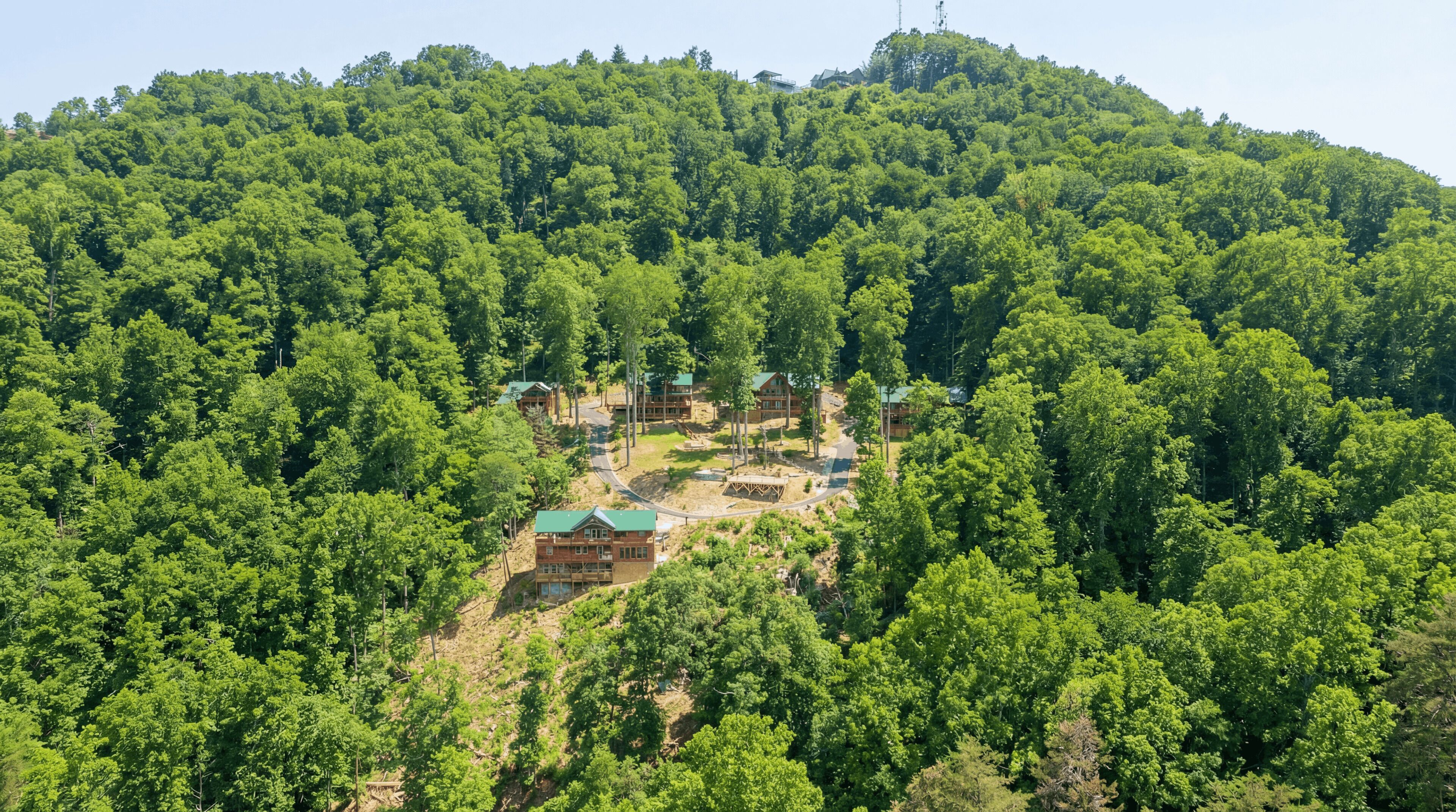 A lodge nestled in a forested hillside with multiple buildings and a winding road.