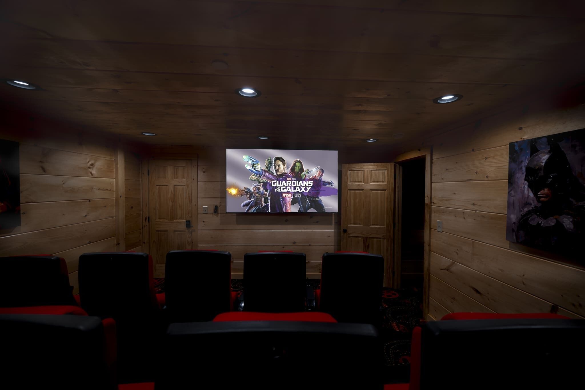A movie theater with wooden walls, a large screen, and red seats.