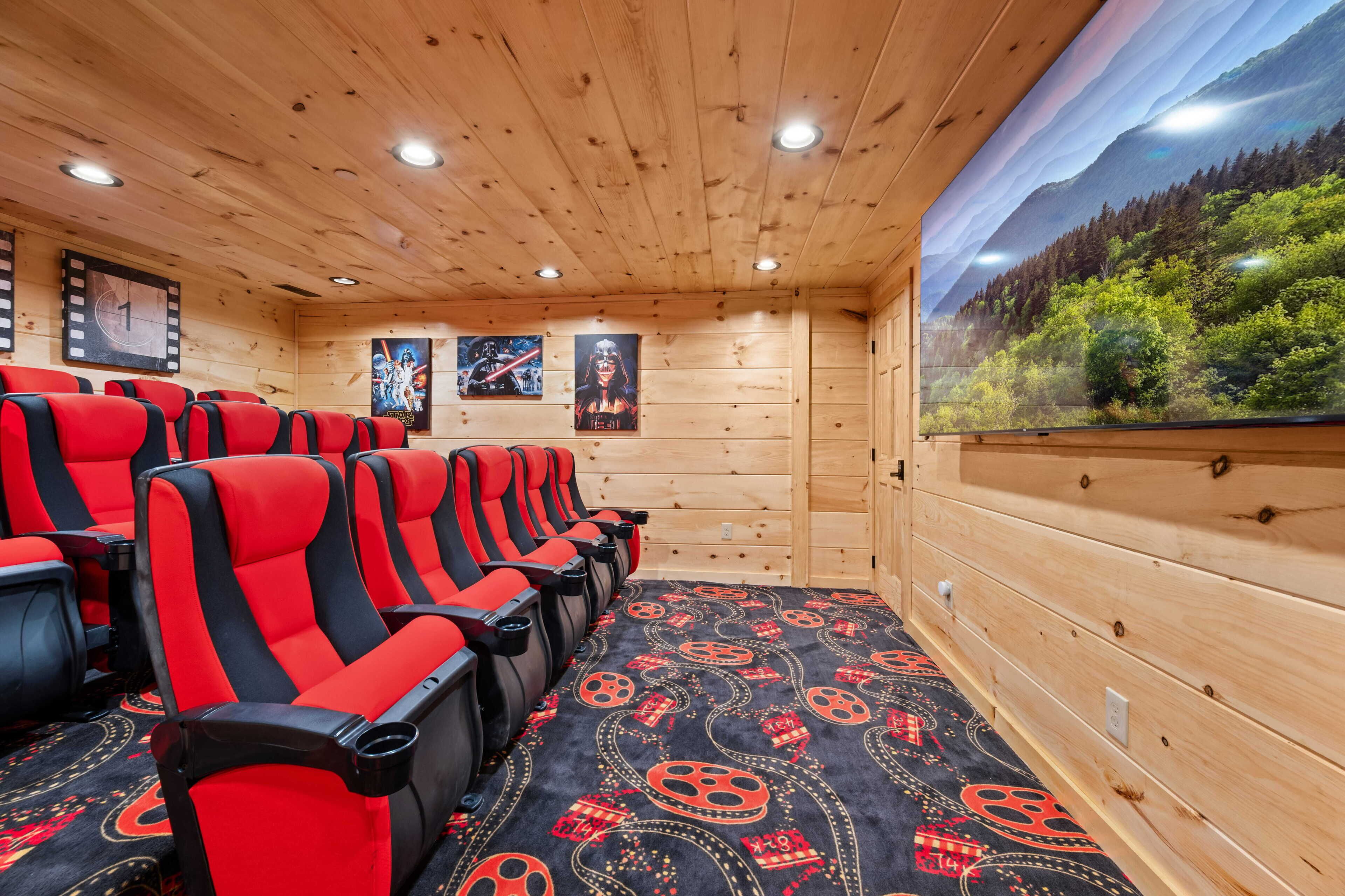 Une salle de cinéma aux murs en bois, avec des sièges rouges et noirs et des affiches accrochées aux murs.