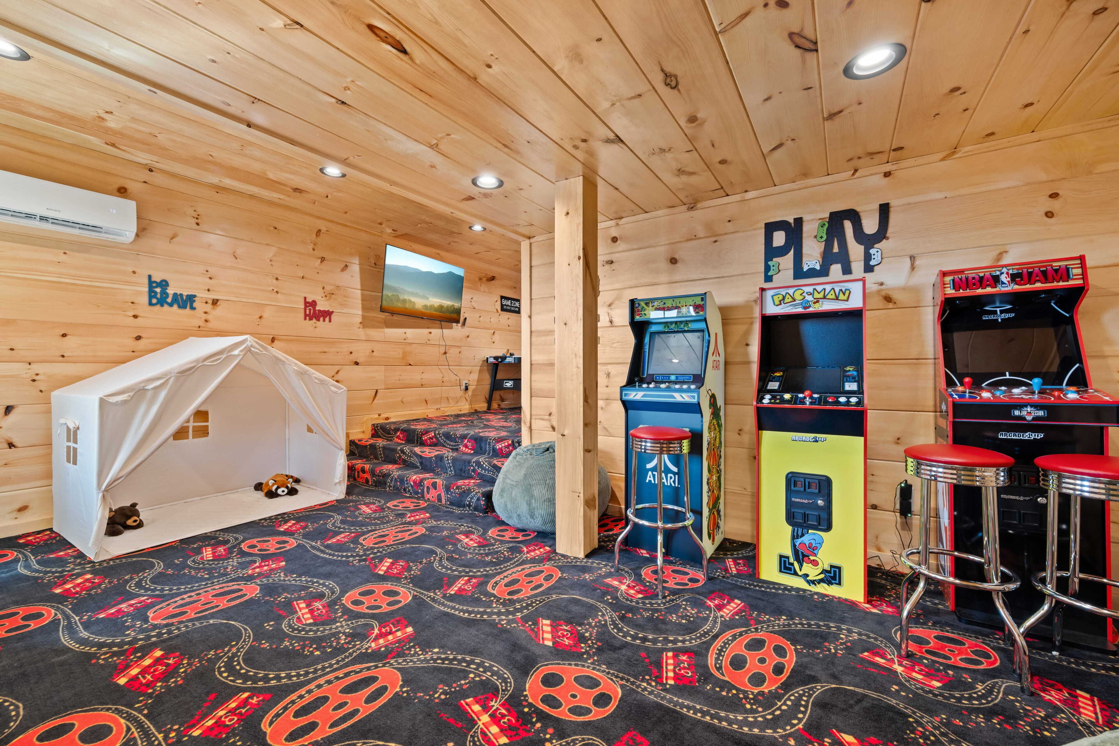 Ein Holzinterieur mit Zelt, Spielautomaten und einer PlayStation.