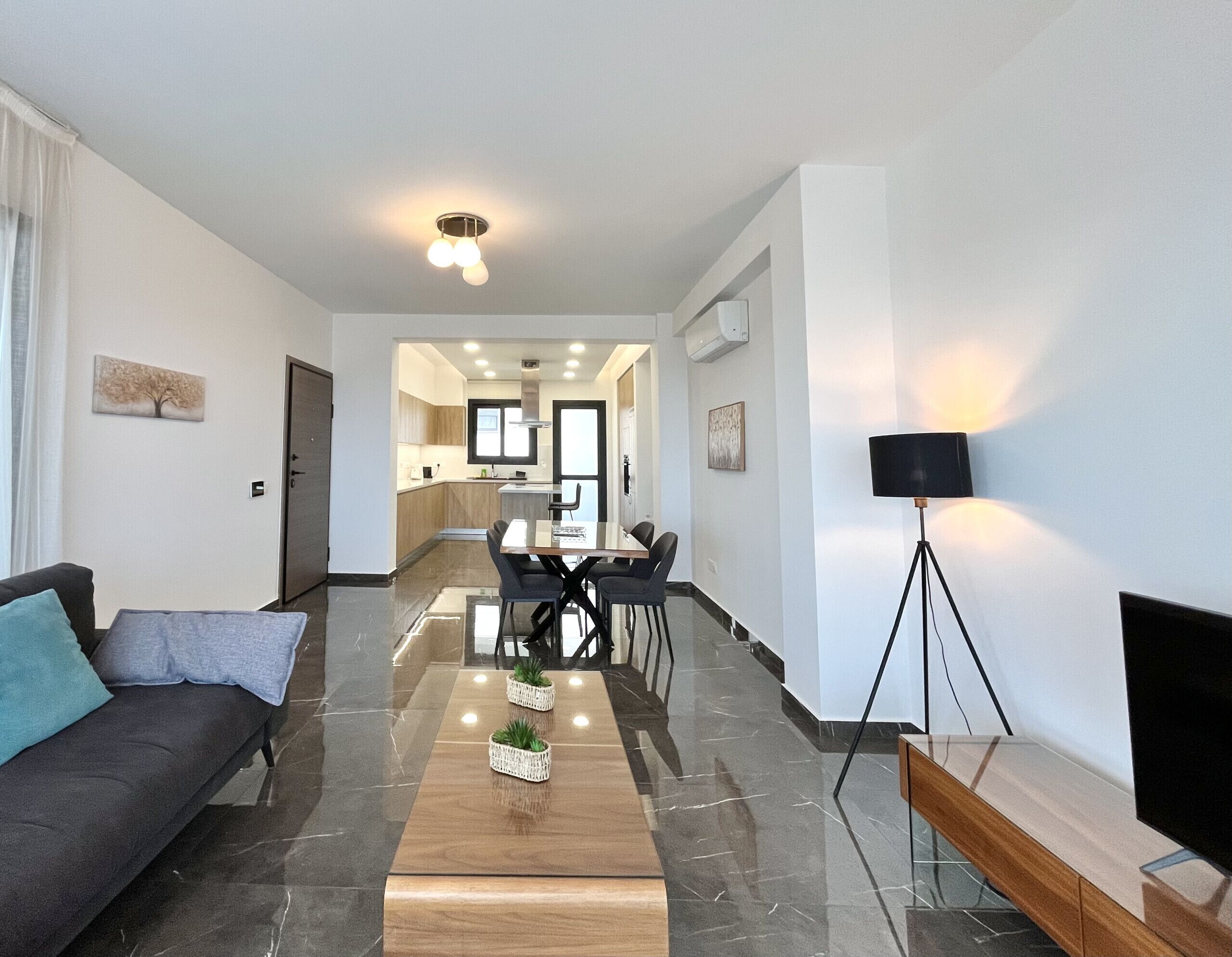 Un salon moderne comprenant un canapé, une table basse et un coin repas avec des chaises et une table.