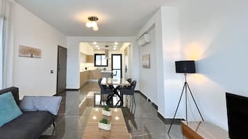 Un salon moderne comprenant un canapé, une table basse et un coin repas avec des chaises et une table.
