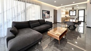 Una sala de estar moderna con un sofá modular, una mesa de centro de madera y un comedor con una mesa y sillas.