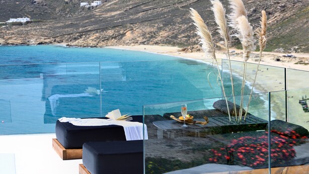 Una piscina infinita de cristal con vistas a una playa y montañas.