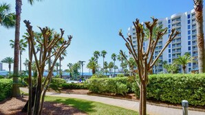 A hotel with a pool area, palm trees, and a clear blue sky. - The Palms of Destin 1111 by Compass Resorts (Destin)